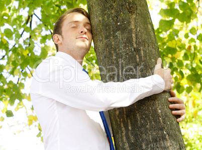 Businessman hugging tree