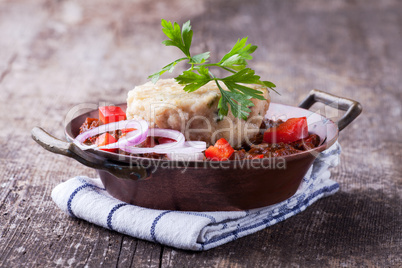 Gulasch mit Knödel auf einem Holzbrett