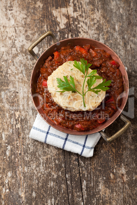 Gulasch mit Knödel auf einem Holzbrett