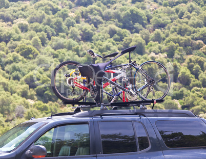 Three bicycles on the top of car near forest