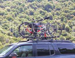 Three bicycles on the top of car near forest