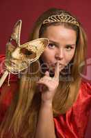 beautiful girl with carnival mask shows gesture of silence