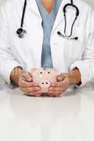 Doctor with Caring Hands on a Piggy Bank