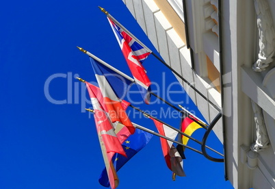 Flaggen und Fahnen an einem Gebäude im Wind vor blauen Himmel
