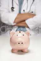 Doctor with Folded Arms Behind Piggy Bank