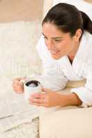 Attractive woman in white bathrobe on sofa