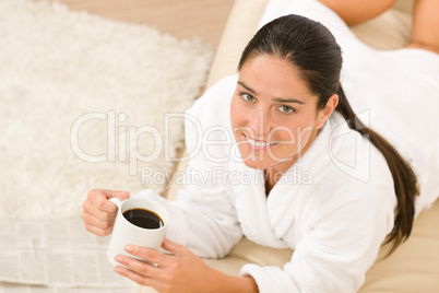 Attractive woman in white bathrobe on sofa