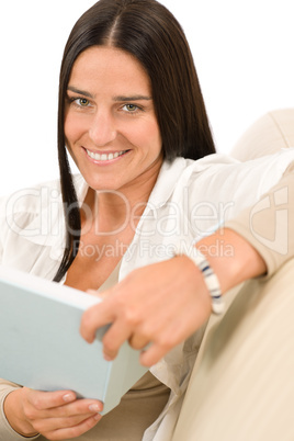 Happy woman with book sitting on sofa