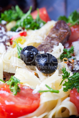 closeup of fresh pasta with tomatos and olives