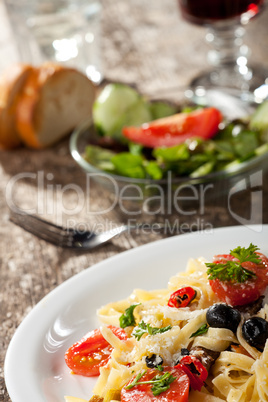 fresh pasta with tomatos and olives on a plate