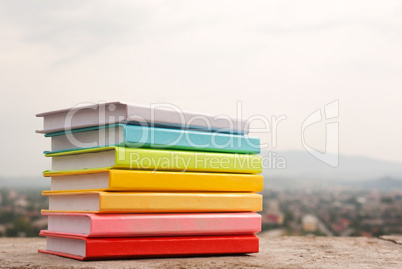 Stack of colorful books laying outdoors