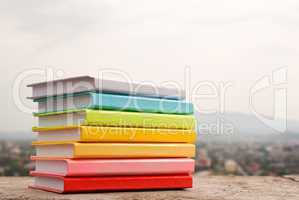 Stack of colorful books laying outdoors