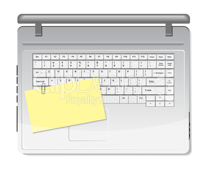 Yellow memo and paper clip on white keyboard