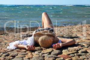 Woman in straw hat lying on the beach