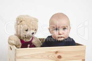 young child with toy in wooden box