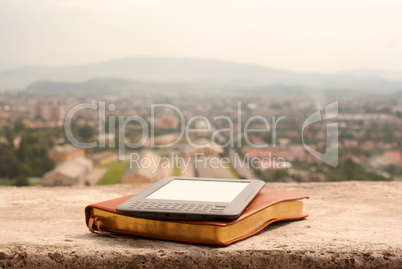 Electronic book reader laying on the book outdoors