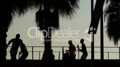 Football players on the beach at sunset