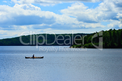 Canoeist Paddle on Calm Wilderness Lake