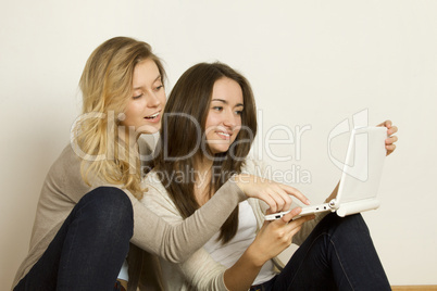 Two attractive friends at home with laptop