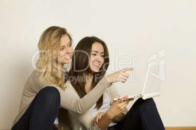 Two attractive friends at home with laptop