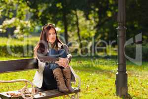 Autumn sunset park woman sitting on bench