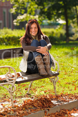 Autumn sunset park woman sitting on bench