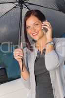 Businesswoman smiling under umbrella call phone