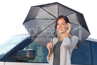 Businesswoman under umbrella by luxury car calling