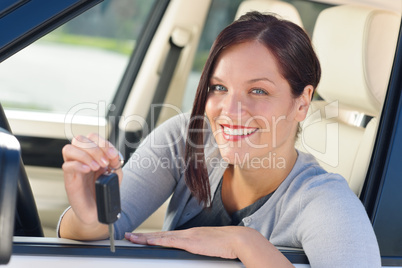 Attractive businesswoman in new car showing keys