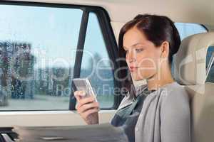 Attractive executive businesswoman sitting in car calling phone checking newspapers