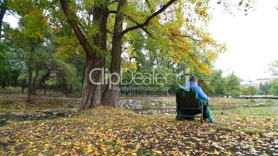 elderly woman resting at autumn park