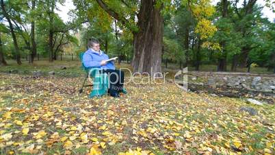 Senior Woman Reading Book in Autumn Park