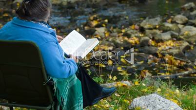 old woman reading  book in autumn park