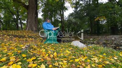 DOLLY: Senior Woman Reading Book in Autumn Park