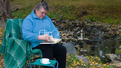 Senior woman reading  book  with cup of coffee