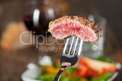 Steak auf einer Gabel über Salat