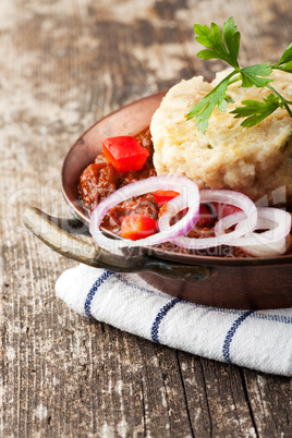 Gulasch mit Knödel auf Holz