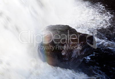 Rainbow over rock in waterfall