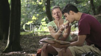 Couple looking at map and eating snack after trekking