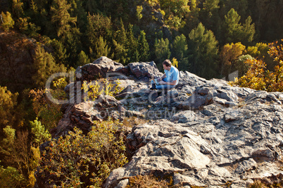 young man using laptop sitting on a rock slope