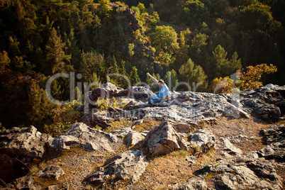 young man using laptop sitting on a rock slope