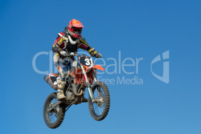 Motorcycle jumping against blue sky