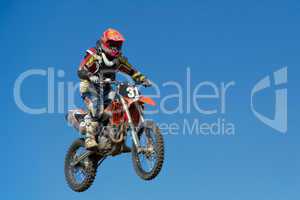 Motorcycle jumping against blue sky