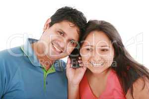 Couple are listening to a friend on a cell phone.