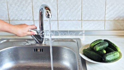 hands of woman wash green cucumber