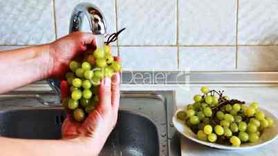 hands of woman wash green grapes