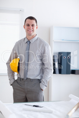 Architect standing and carrying a helm