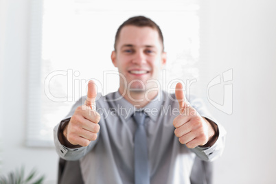 Young businessman giving thumbs up