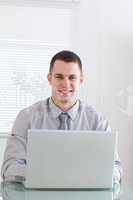 Close up of smiling businessman working on his laptop