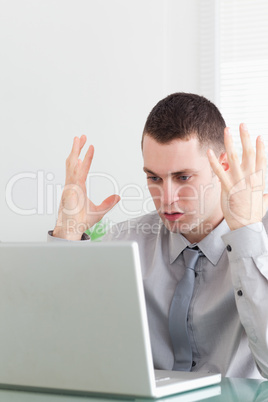 Close up of young businessman having problems with his laptop